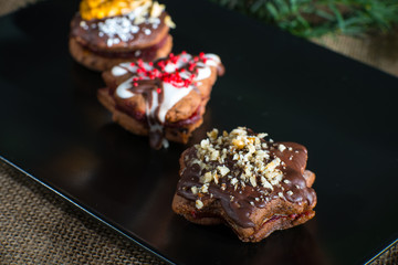 Christmas cookies with marmolade on a black plate background.