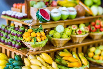 close up Miniature clay figurine Thailand's floating market,Miniature boat carrying tropical fruit on wood background