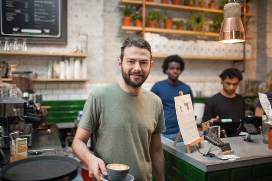 Portrait of  male barista serving coffee in cafe