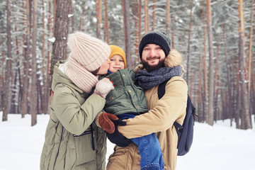 Fototapeta na wymiar Merry family playing together on a sunny snowy day in the forest