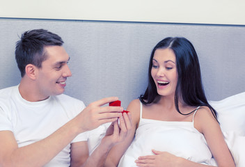 man giving woman little red box and ring in it
