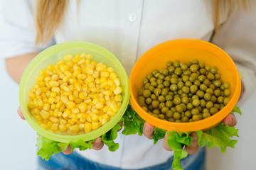 girl holding canned peas and corn closeup
