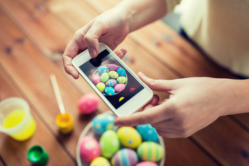 close up of hands with easter eggs and smartphone