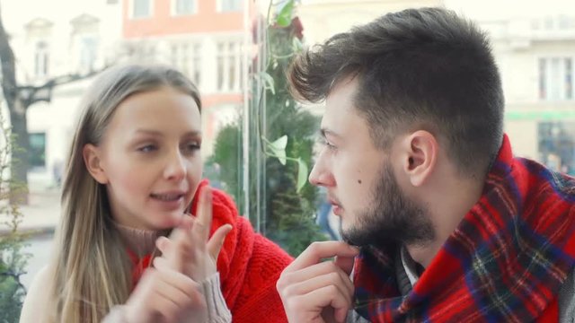 Couple sitting in the outdoor cafe and talking about something, steadycam shot
