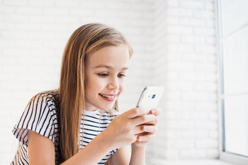 Cute little girl using smart phone at home