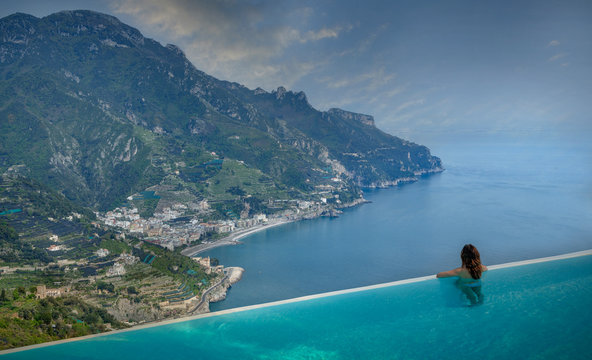 Rear view of woman looking out to coast from infinity pool, Ravello, Amalfi coast, Italy