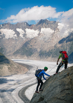 Couple climbing up ridge over Aletsch Glacier, Canton Wallis, Switzerland