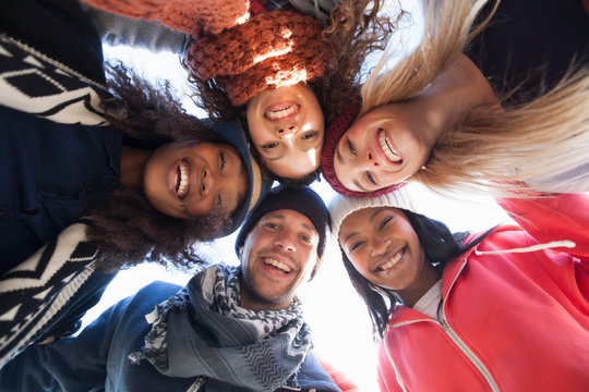 Low angle portrait of five happy adult friends huddled in a circle