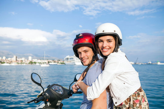 Portrait of young couple riding moped at harbour, Split, Dalmatia, Croatia