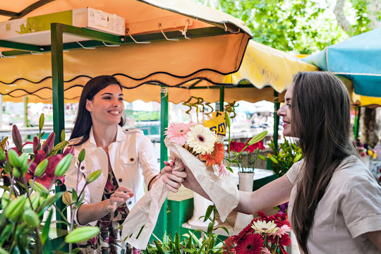 Stall holder handing female tourist bunch of flowers at market stall, Split, Dalmatia, Croatia