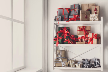 Christmas gift boxes on white shelves at wall background