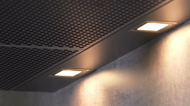 A young woman is turning on the light on a kitchen hood. Then she turns it off again.
