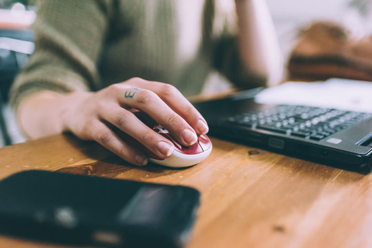 Hand of young woman using laptop mouse
