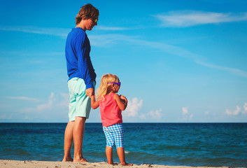 Father and little daughter walk on beach