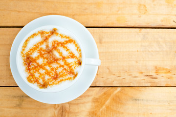 Hot caramel machiato on the wooden table with morning sunlight  (top view)