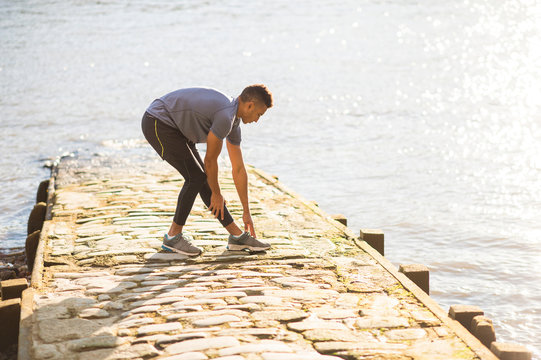 Man stretching on pier, Wapping, London, UK