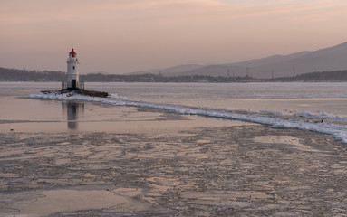 Lighthouse at sunset. Winter season.