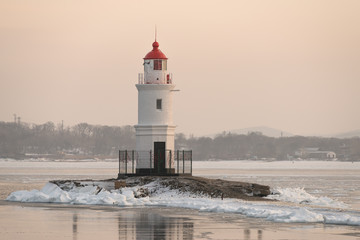 Lighthouse at sunset. Winter season.