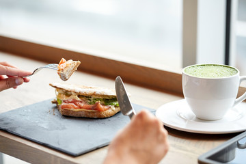 woman eating salmon panini sandwich at restaurant