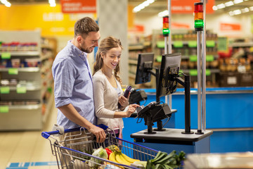 couple buying food at grocery at cash register - obrazy, fototapety, plakaty