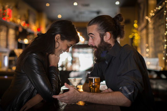 Young couple talking at table with cocktail and beer in public house