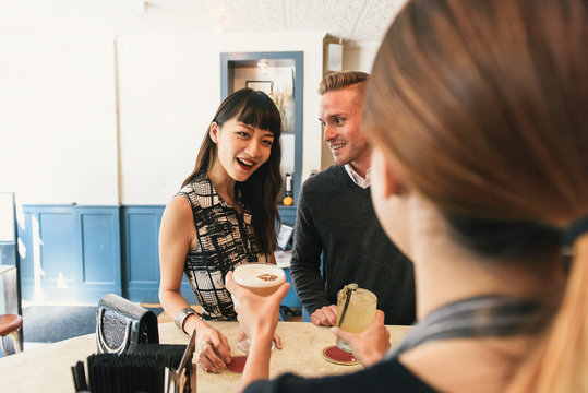 Young couple in bar, bring served drinks by bar worker