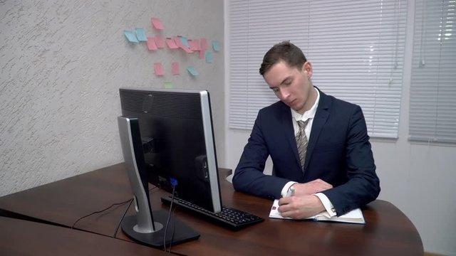 Young man making notes in his notebook in teh office