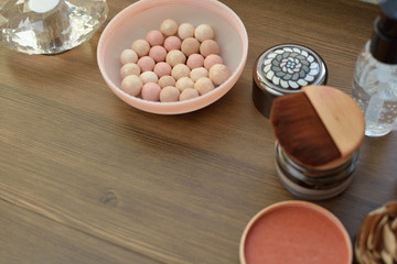 cosmetics on wooden table: powder, lipstick, eye shadow and perfume