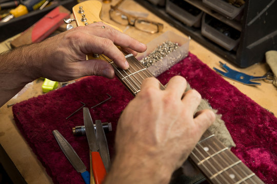 Cropped view of guitar maker's hands manufacturing guitar