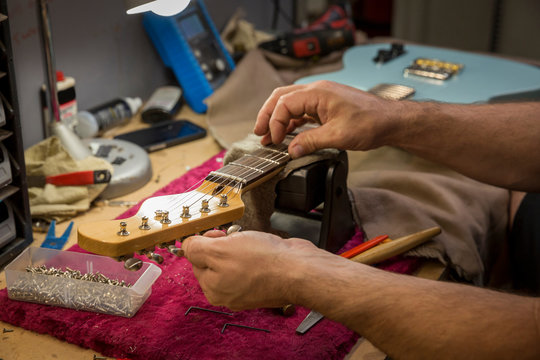 Cropped view of guitar maker's hands manufacturing guitar