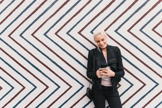 Woman in front of zig zag pattern wall using smartphone