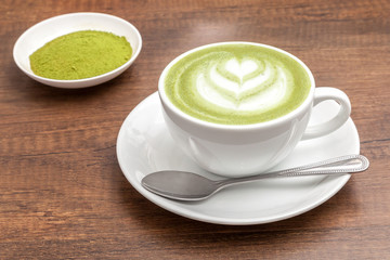 reen tea / Matcha latte in a cup with matcha powder on the wooden table