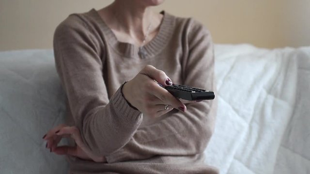 Happy woman watching TV on sofa at home