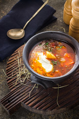 Soup in clay bowl on chopping board.