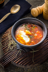 Soup in clay bowl on chopping board.
