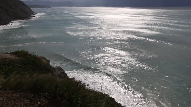 Summer ocean coastline view with evening sun reflection on water surface, Biscay bay, Spain.
