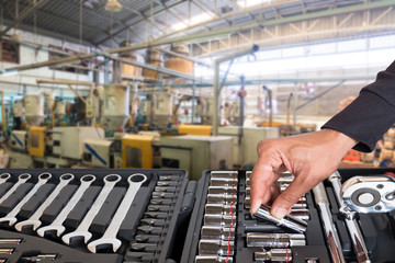 Hand of a man who handled tools with blurred of factory for background.