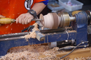 電動ろくろで木を削る職人