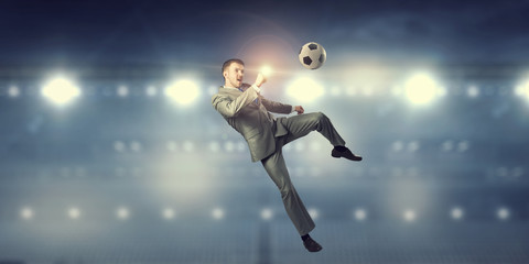 Fototapeta na wymiar Businessman kicking ball . Mixed media