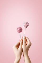 Woman hands holding pop cakes on pastel background