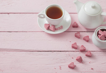 Fototapeta na wymiar Granulated pink sugar in the shape of heart and cup of tea on