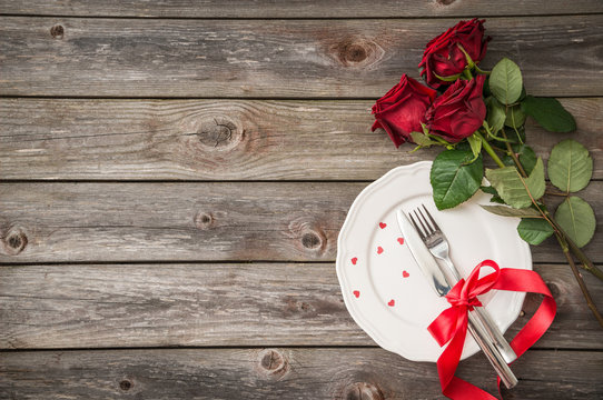 romantic table setting with a white dish and red roses