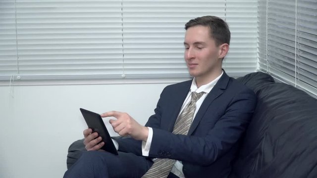 Businessman working on tablet on the sofa in the office
