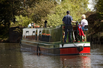 Fototapeta premium Aged couple on narrow boat in canal, England