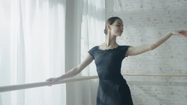 Mid Shot of a Young and Beautiful Ballerina Dancing at the Barre. Shot on Warm and Sunny Morning in a Spacious and Modern Studio. Shot on RED EPIC-W 8K Helium Cinema Camera.