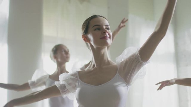  Mid Shot of Three Beautiful and Young Ballerinas Wearing White Tutus and Dancing. Shot on a Sunny Morning in a Spacious and Bright Studio. In Slow Motion. Shot on RED EPIC-W 8K Helium Cinema Camera.