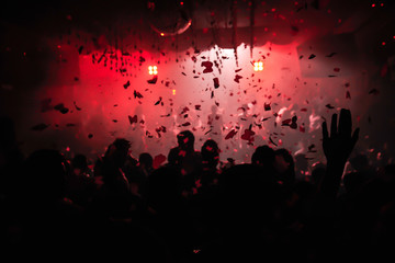 Confetti fired on air during a party in a disco. Confetti for background. Silhouette of happy...