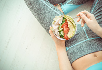 Young woman is resting and eating a healthy salad after a workout. Fitness and healthy lifestyle...