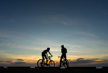 Fototapeta na wymiar Silhouettes of Cyclists on bicycle at the ocean in the sunset sc