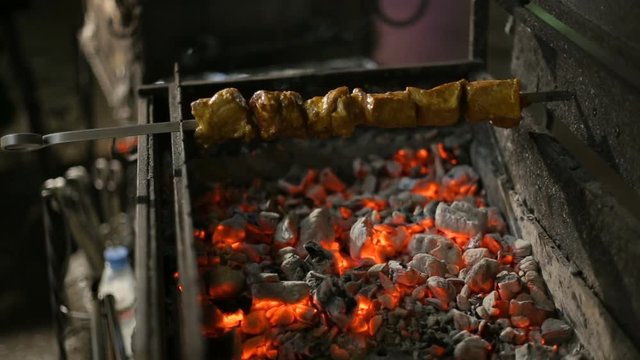 A Barbecue Skewer Spinning On The Grill. Fresh Steaming Meat BBQ. Street Cart With Grill.